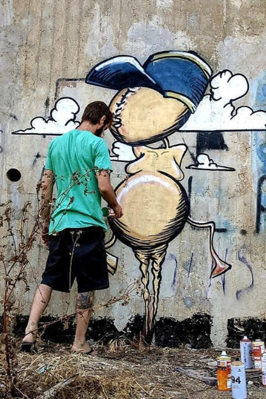 Damian Tab street art mural in Hadera Israel featuring seed character as a driver in surreal urban scene